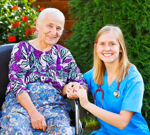 elderly woman on a wheelchair and a nurse smiling